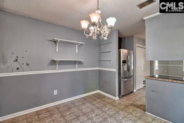 kitchen featuring an inviting chandelier, tile patterned floors, a textured ceiling, stainless steel fridge with ice dispenser, and hanging light fixtures