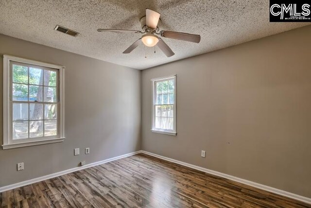 empty room with hardwood / wood-style flooring, plenty of natural light, and a textured ceiling