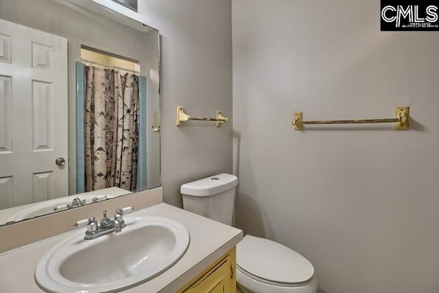 bathroom featuring curtained shower, vanity, and toilet