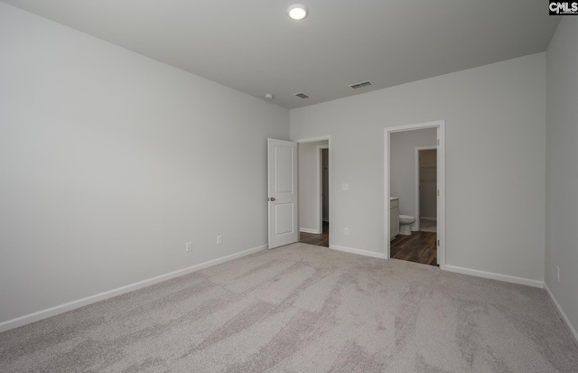 unfurnished bedroom featuring light carpet and ensuite bath