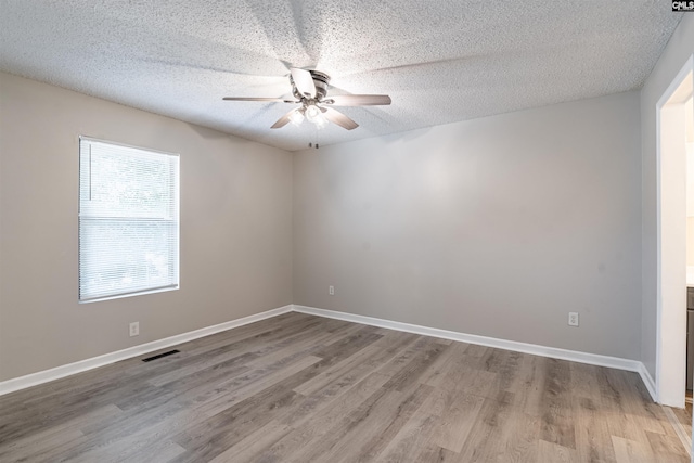 empty room with ceiling fan, a textured ceiling, and hardwood / wood-style floors