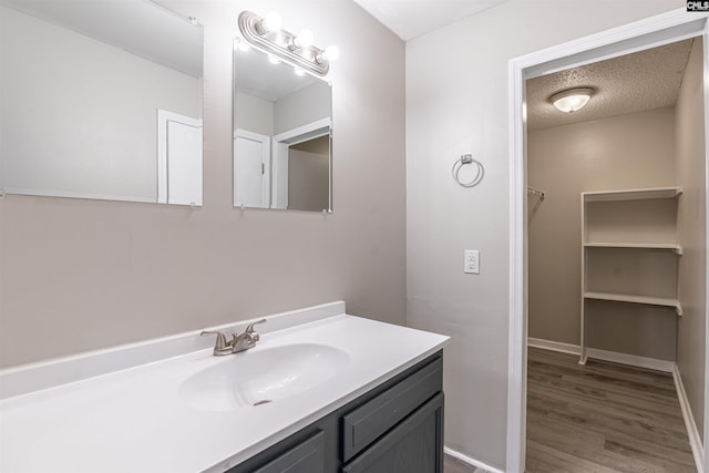 bathroom with hardwood / wood-style flooring, a textured ceiling, and vanity