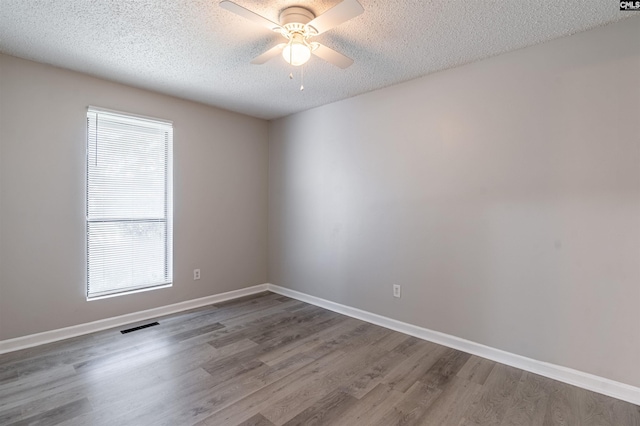 empty room featuring hardwood / wood-style floors, plenty of natural light, ceiling fan, and a textured ceiling