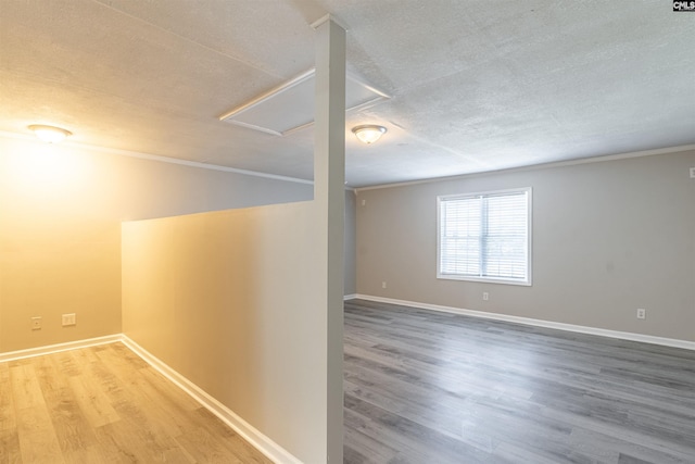 spare room featuring a textured ceiling, hardwood / wood-style floors, and ornamental molding