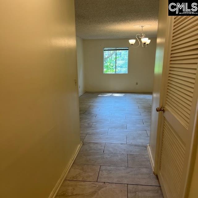 1208 Bush River Rd Unit F-7, Columbia, SC 29210 - corridor featuring baseboards, a chandelier, and a textured ceiling