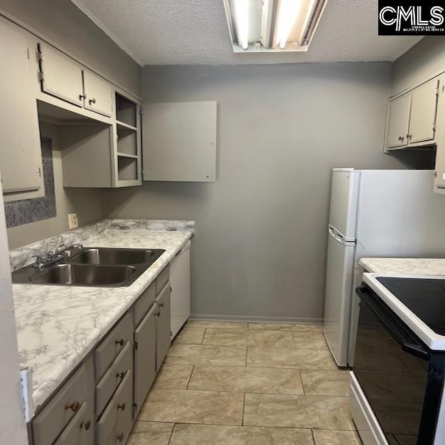 1208 Bush River Rd Unit F-7, Columbia, SC 29210 - kitchen with black range oven, a sink, a textured ceiling, light countertops, and baseboards