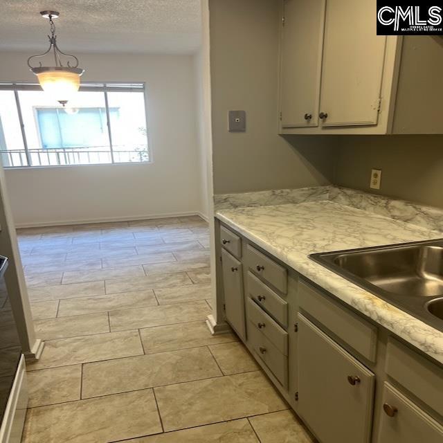 1208 Bush River Rd Unit F-7, Columbia, SC 29210 - kitchen with light countertops, a textured ceiling, pendant lighting, and baseboards