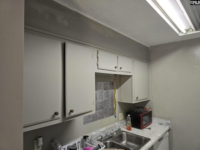 kitchen with sink, white cabinets, a textured ceiling, and dishwasher