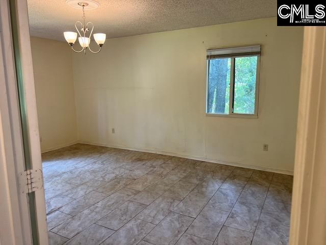 1208 Bush River Rd Unit F-7, Columbia, SC 29210 - unfurnished room with a textured ceiling, a chandelier, and baseboards