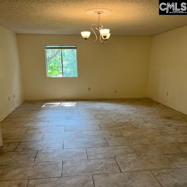 1208 Bush River Rd Unit F-7, Columbia, SC 29210 - unfurnished room featuring a chandelier, a textured ceiling, and baseboards