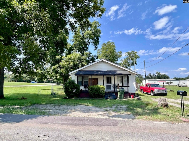 bungalow-style home featuring a front yard and covered porch