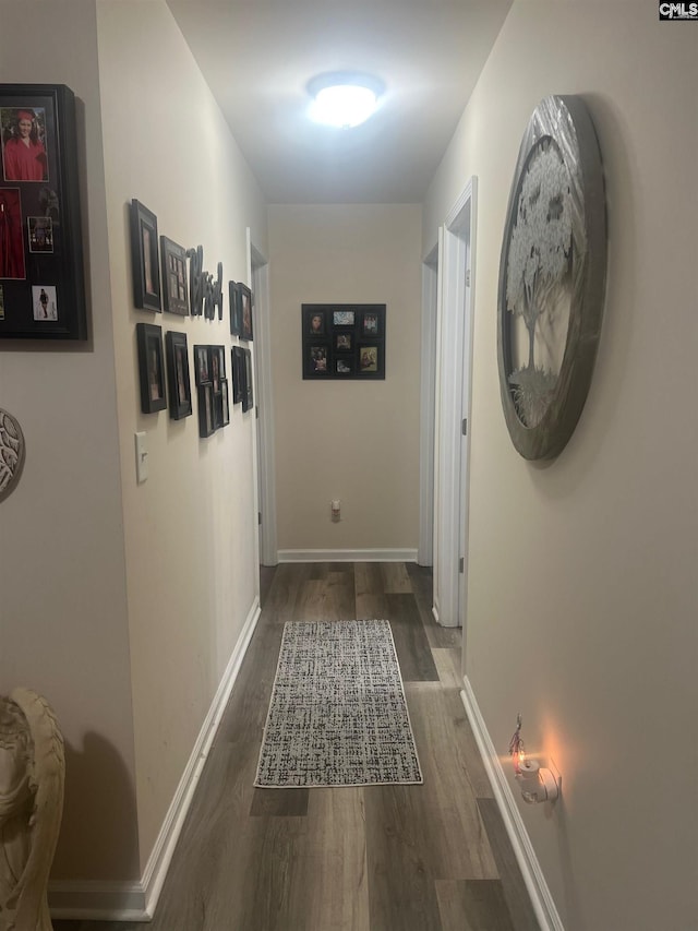 corridor with baseboards and wood finished floors