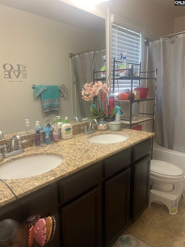 bathroom featuring double vanity, tile patterned flooring, toilet, and a sink