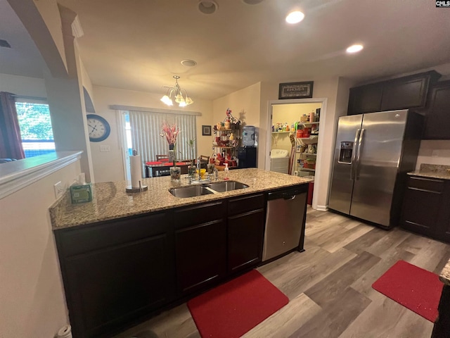 kitchen featuring recessed lighting, a sink, appliances with stainless steel finishes, light stone countertops, and light wood finished floors