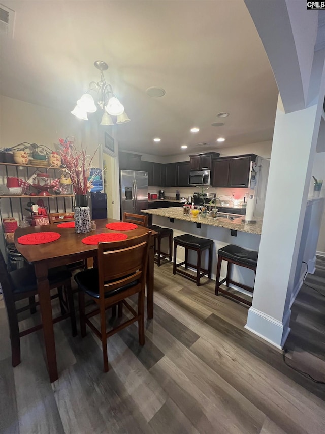 dining area featuring a chandelier, recessed lighting, wood finished floors, visible vents, and baseboards