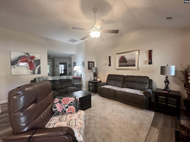 living room featuring visible vents, light wood-style flooring, vaulted ceiling, ceiling fan, and baseboards