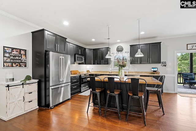 kitchen featuring hardwood / wood-style flooring, hanging light fixtures, a kitchen bar, and stainless steel appliances