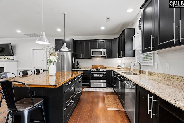 kitchen featuring appliances with stainless steel finishes, sink, dark hardwood / wood-style flooring, a kitchen island, and a breakfast bar area