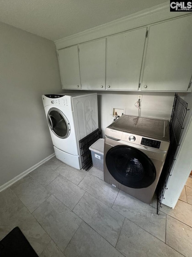 laundry room with washing machine and dryer, light tile patterned flooring, and cabinets