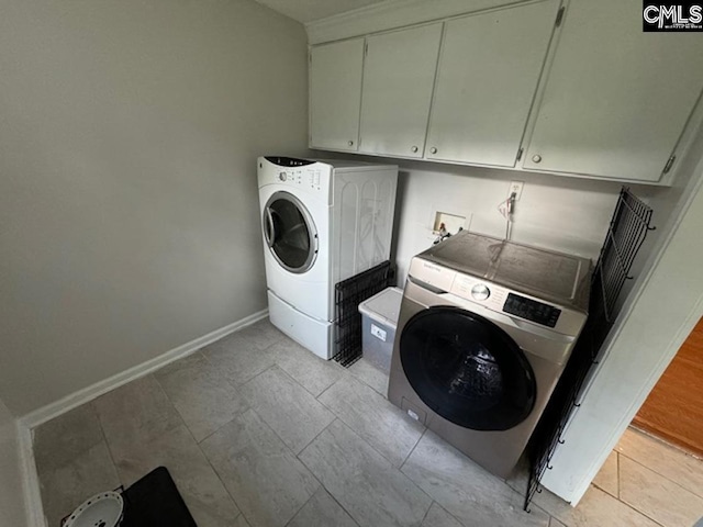 washroom with light tile patterned floors, cabinets, and washer and dryer