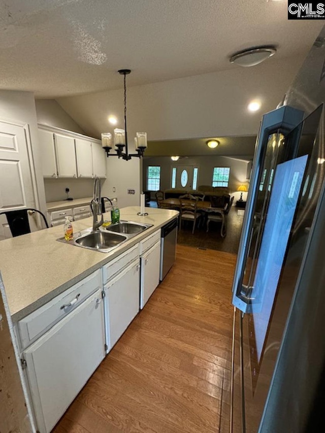 kitchen with an island with sink, white cabinets, hardwood / wood-style flooring, decorative light fixtures, and sink