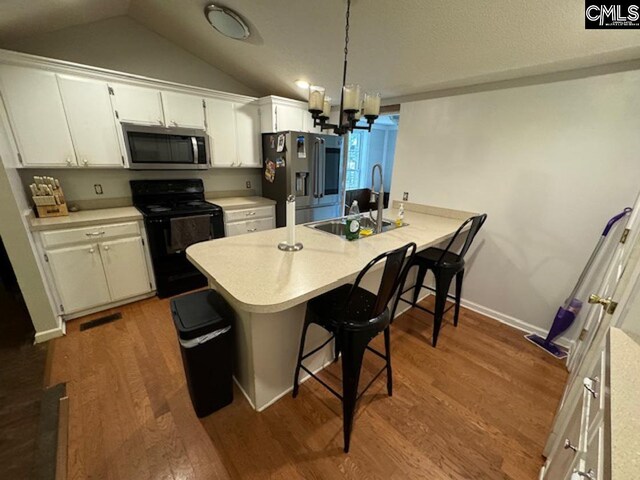 kitchen featuring hardwood / wood-style floors, appliances with stainless steel finishes, sink, kitchen peninsula, and an inviting chandelier