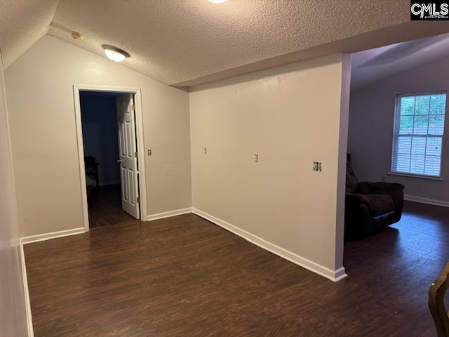 interior space featuring a textured ceiling, lofted ceiling, and dark wood-type flooring