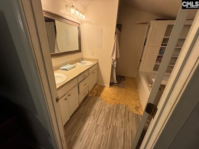 bathroom with vaulted ceiling, a bathing tub, and vanity