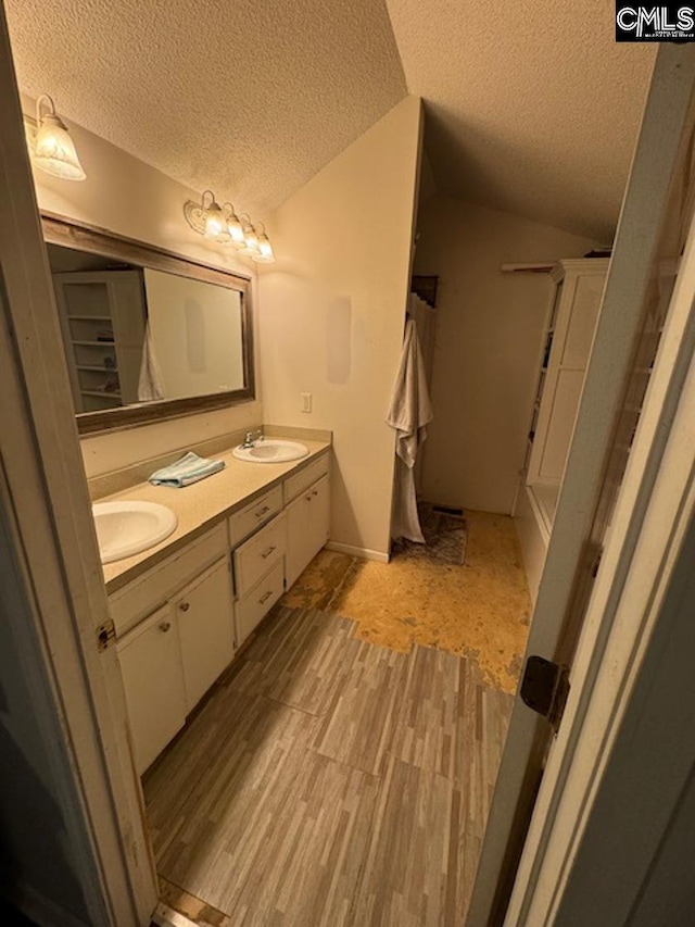 bathroom featuring a textured ceiling, lofted ceiling, and vanity