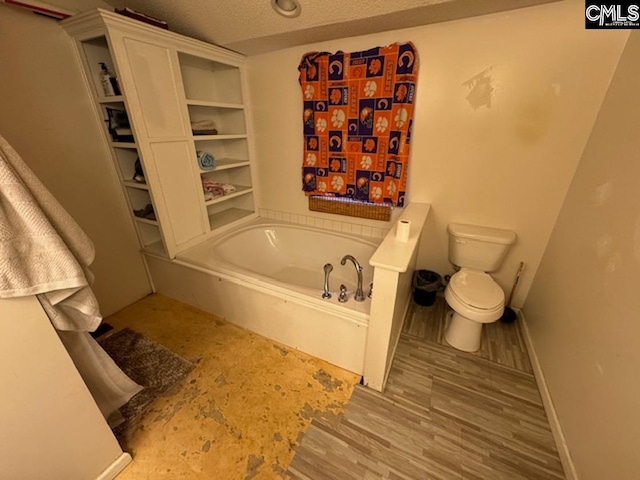 bathroom with a tub, toilet, a textured ceiling, and wood-type flooring