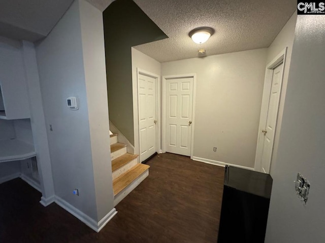 corridor with dark hardwood / wood-style floors and a textured ceiling