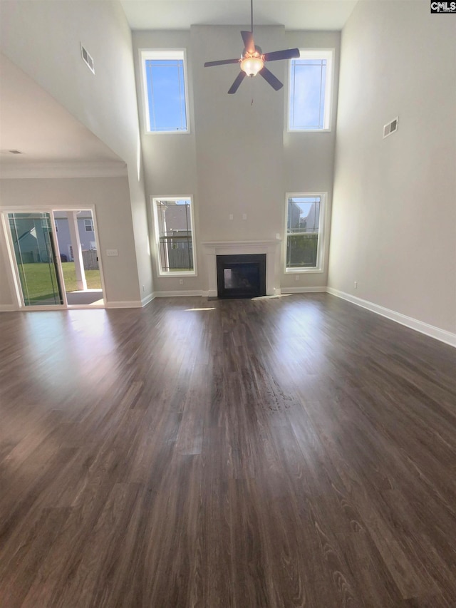 unfurnished living room with a towering ceiling, dark hardwood / wood-style flooring, and ceiling fan