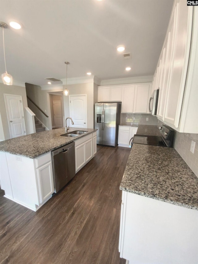 kitchen with dark wood-type flooring, appliances with stainless steel finishes, an island with sink, and tasteful backsplash