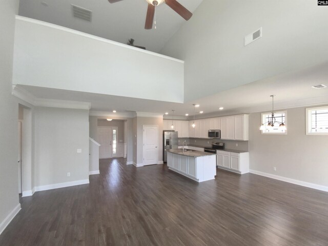 unfurnished living room with ceiling fan with notable chandelier, dark hardwood / wood-style flooring, sink, and a high ceiling