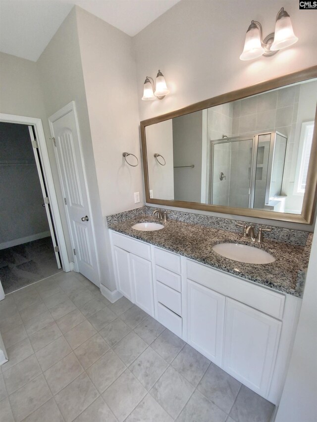 bathroom featuring a shower with shower door, vanity, and tile patterned floors