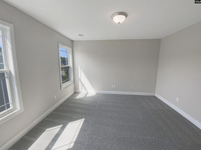 unfurnished room featuring dark carpet