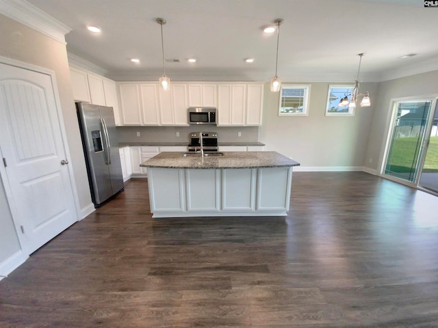 kitchen featuring dark hardwood / wood-style flooring, appliances with stainless steel finishes, white cabinets, an island with sink, and dark stone counters