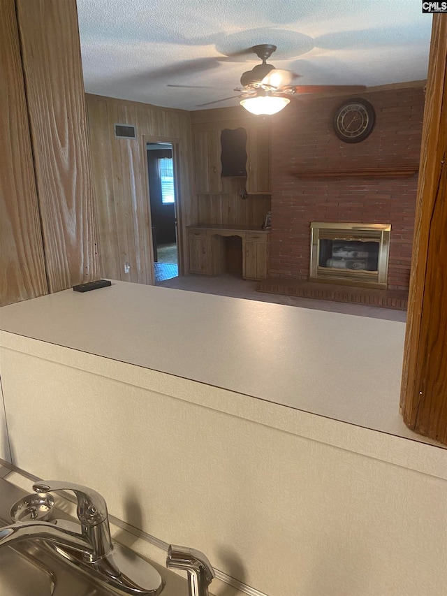 interior space with ceiling fan, a fireplace, wooden walls, and a textured ceiling