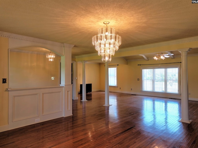 interior space with ornamental molding, a notable chandelier, decorative columns, and wood finished floors
