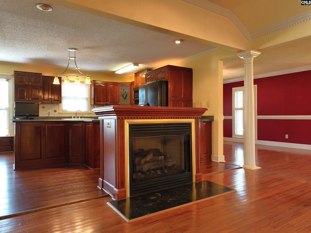 kitchen featuring a sink, decorative columns, black fridge, dark wood-type flooring, and crown molding
