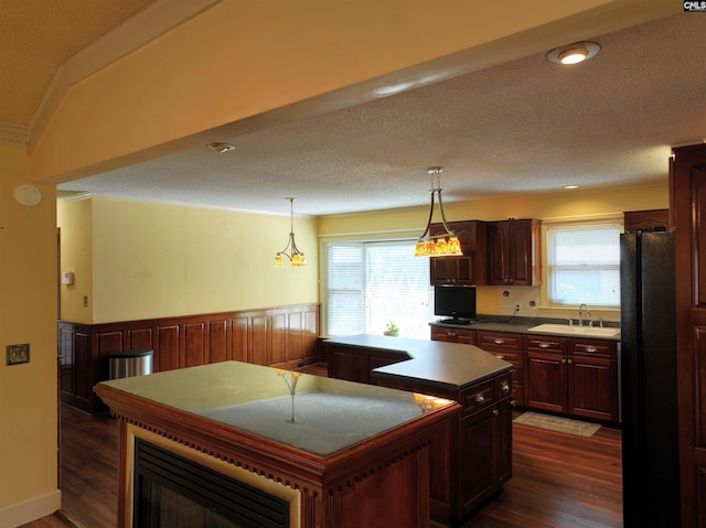 kitchen featuring dark wood-style floors, a center island, a wealth of natural light, and a sink