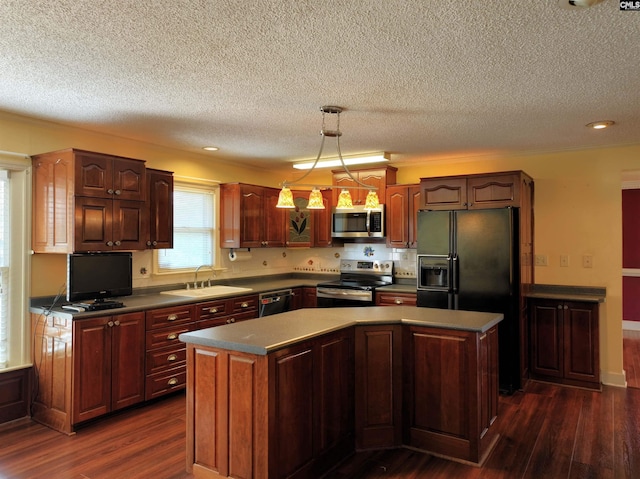 kitchen featuring a textured ceiling, appliances with stainless steel finishes, a kitchen island, and a sink