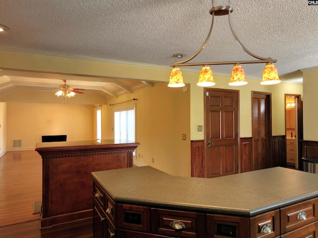 kitchen with beamed ceiling, a textured ceiling, a kitchen island, ceiling fan, and dark hardwood / wood-style floors