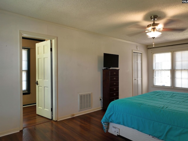 bedroom featuring a textured ceiling, dark wood-type flooring, ceiling fan, and a closet