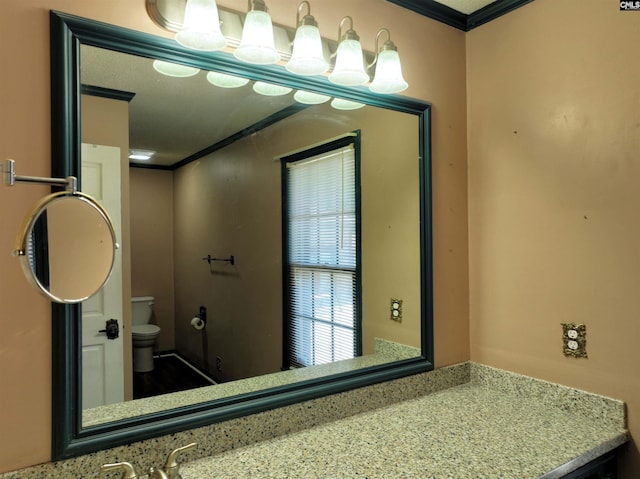 bathroom with vanity, toilet, and ornamental molding