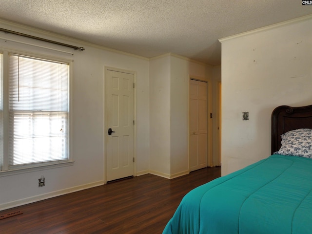 bedroom featuring ornamental molding, dark wood-style floors, a textured ceiling, and baseboards
