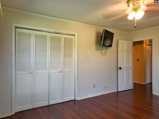 unfurnished bedroom featuring dark wood-type flooring, ceiling fan, ornamental molding, and a closet