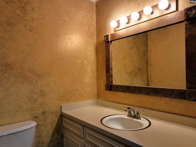 bathroom with toilet, a textured wall, and vanity