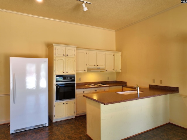 kitchen featuring a sink, under cabinet range hood, crown molding, a peninsula, and white appliances