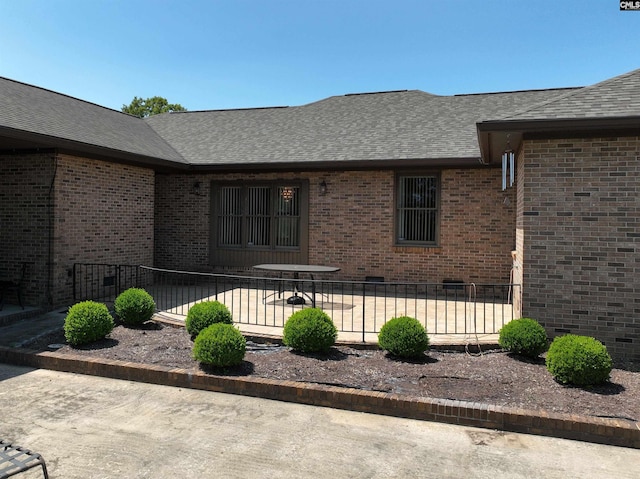 back of property with a patio, brick siding, fence, and roof with shingles